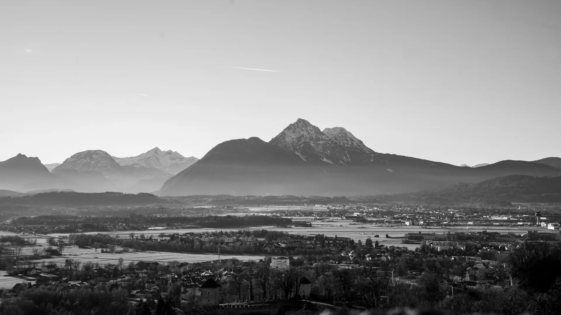 Salzburg from above in black and white, the Untersberg rising behind the town.